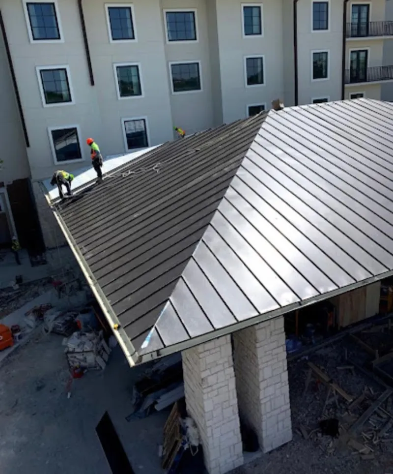 Crew installing standing seam metal roof panels on a commercial project in Asheville